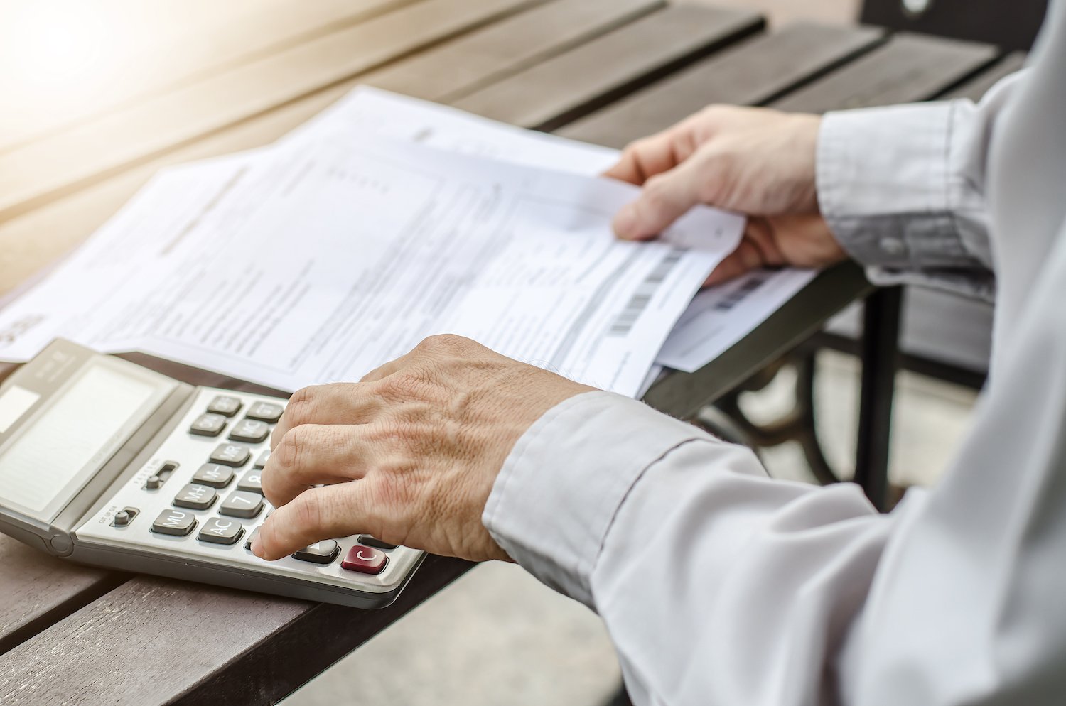 Empleado usando una calculadora mientras sostiene su talonario de pago sobre un escritorio