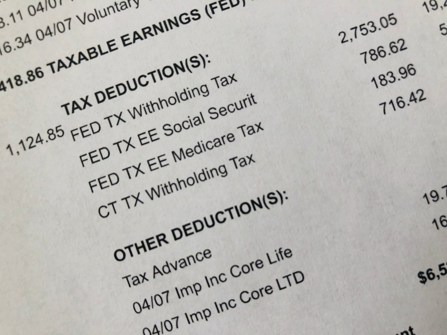 primer plano de un talonario de pago que lista deducciones de impuestos y otras deducciones