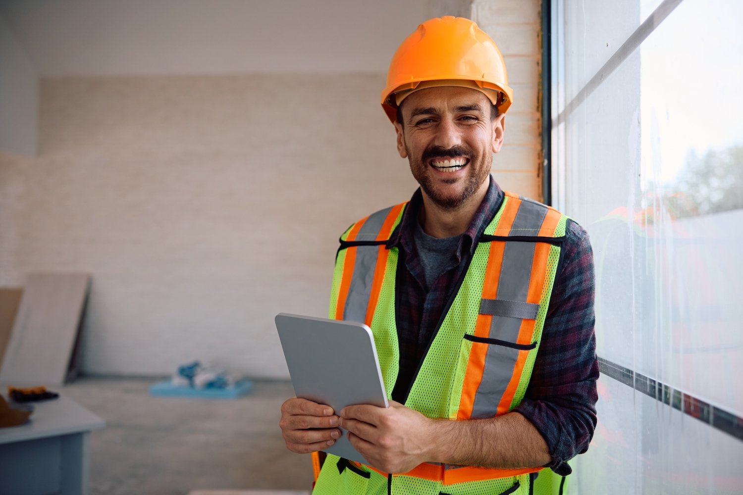 Trabajador de construcción sonriente con casco sosteniendo una tableta