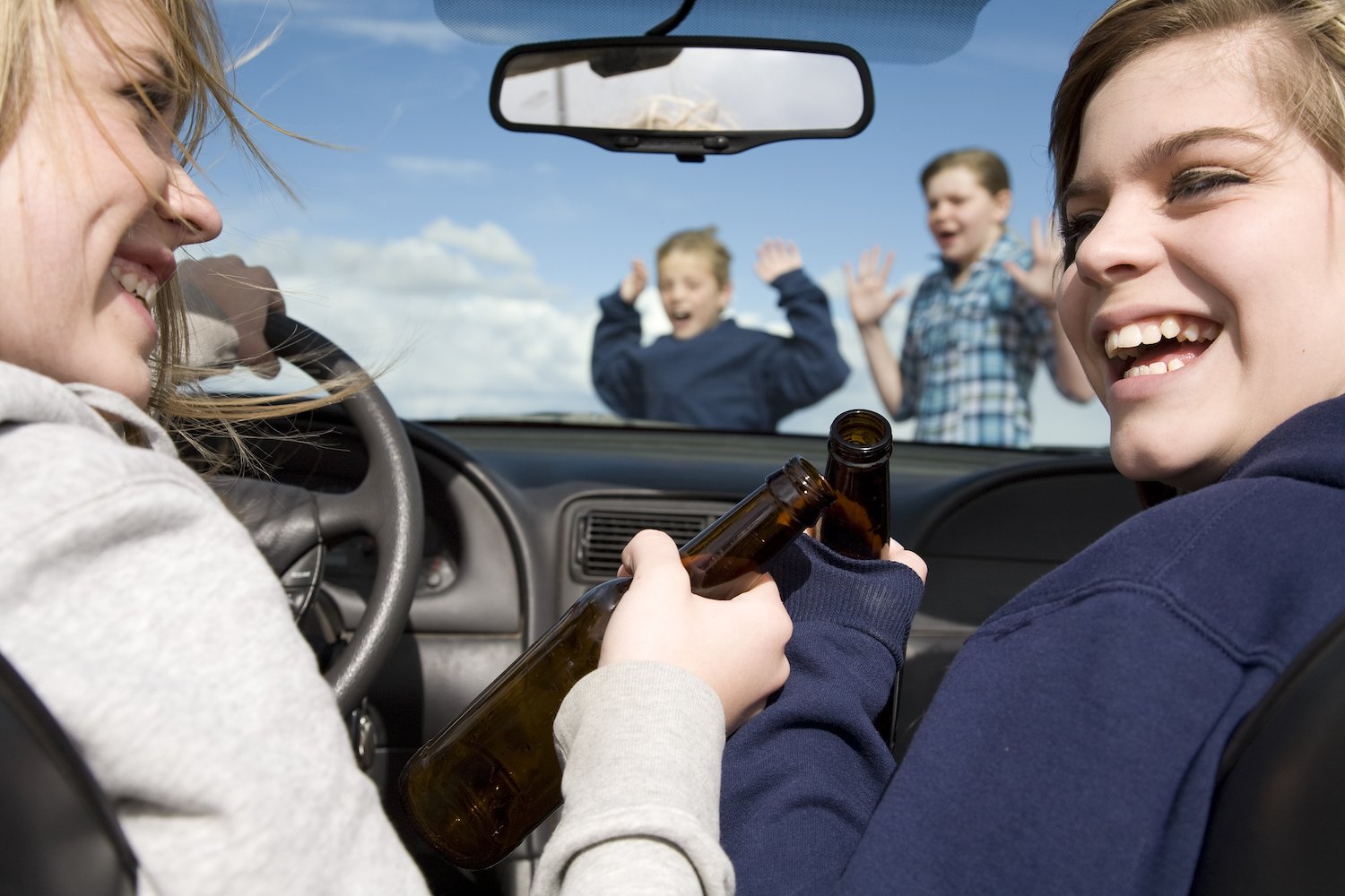Drinking teens behind the wheel of a car about to hit other children as seen through the windshield