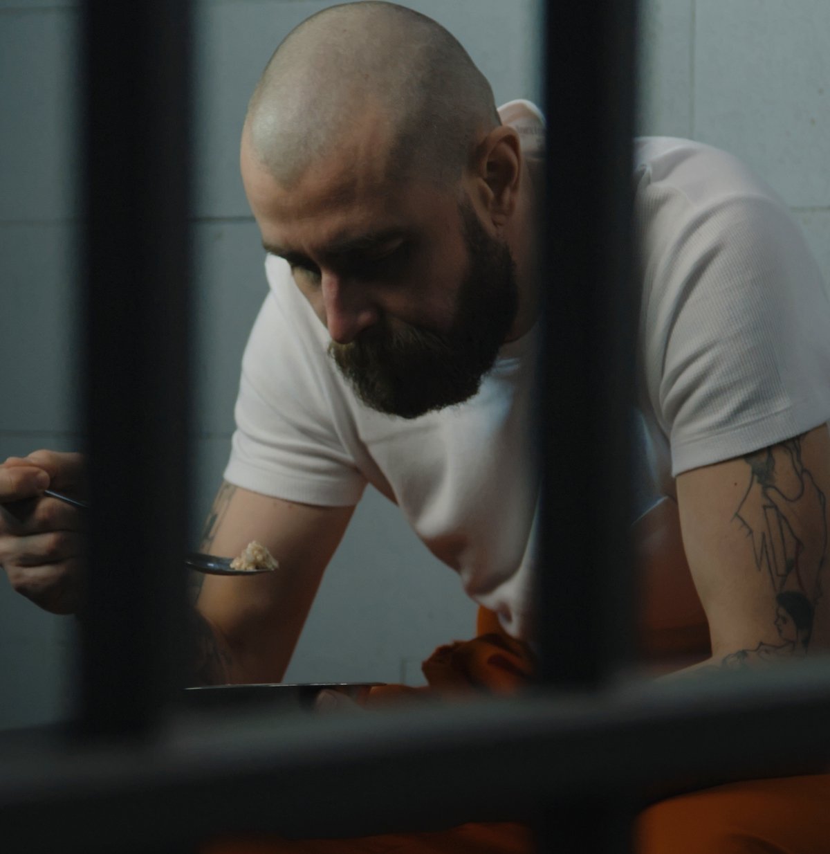 Recluso mirando abatido en su celda tras una condena por asesinato con circunstancias especiales