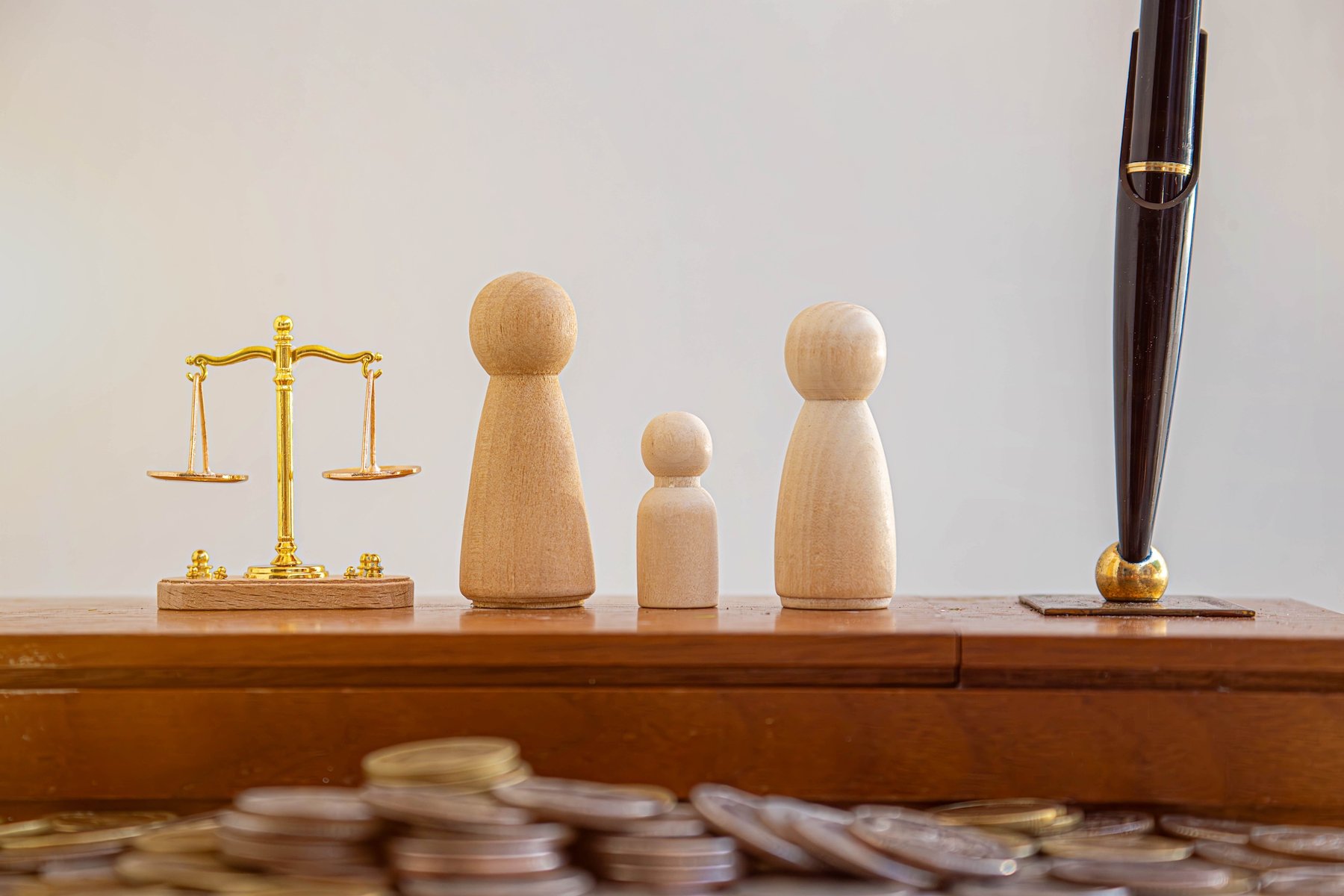 balanza de la justicia junto a representaciones de madera de un niño y tutores