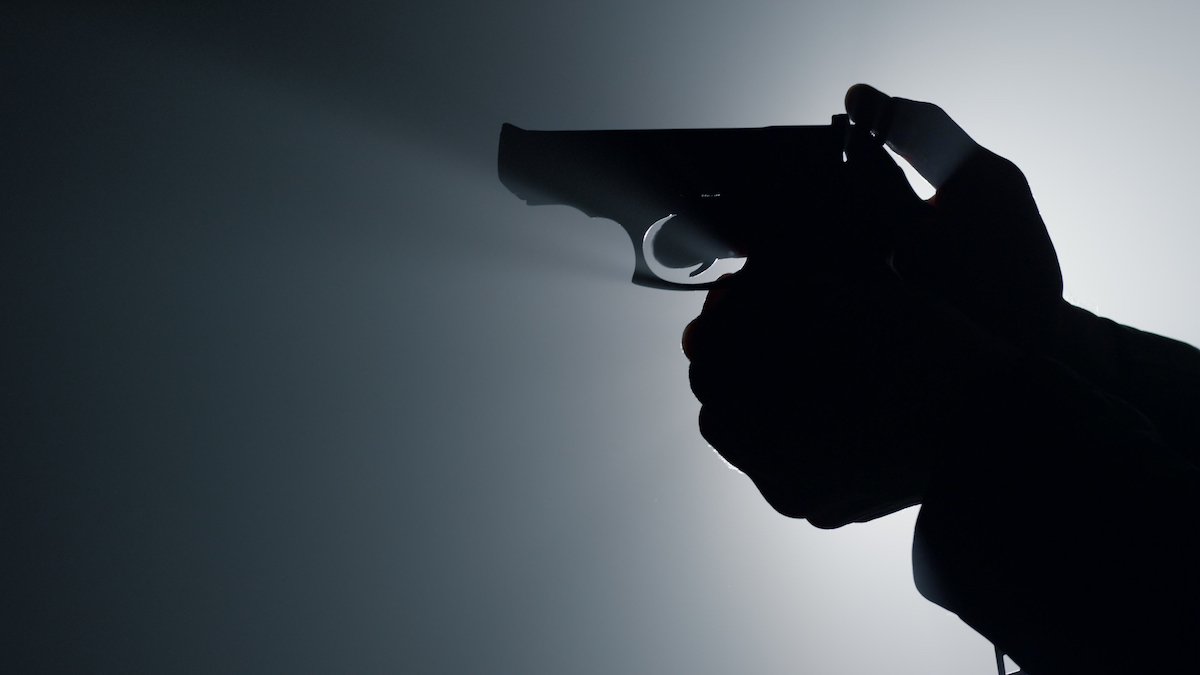 Silueta de hombre sosteniendo una pistola en interiores